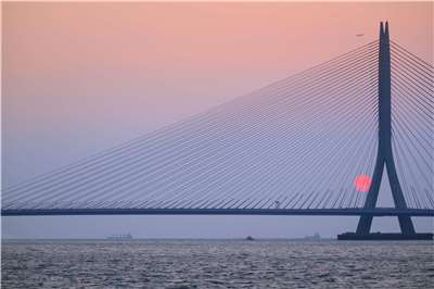 淡江大橋將於5月12日通車，不僅紓解長年交通壅塞，設計團隊還精算全年日落軌跡，打造橋體與夕陽交會的獨特景觀。圖為每年夏至，淡水河口的落日將會剛好落入淡江大橋橋體的開口。(公路局及設研院提供)