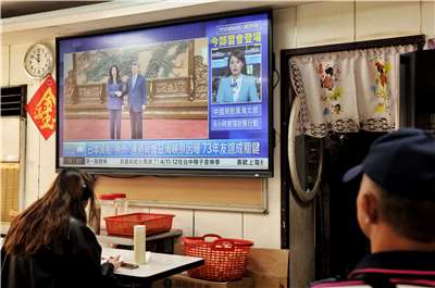 國民黨主席鄭麗文(電視內左)今天(10日)在北京人民大會與中國領導人習近平(電視內右)會面。圖為台灣民眾在小吃關注10日在北京舉行的鄭習會。(AFP)