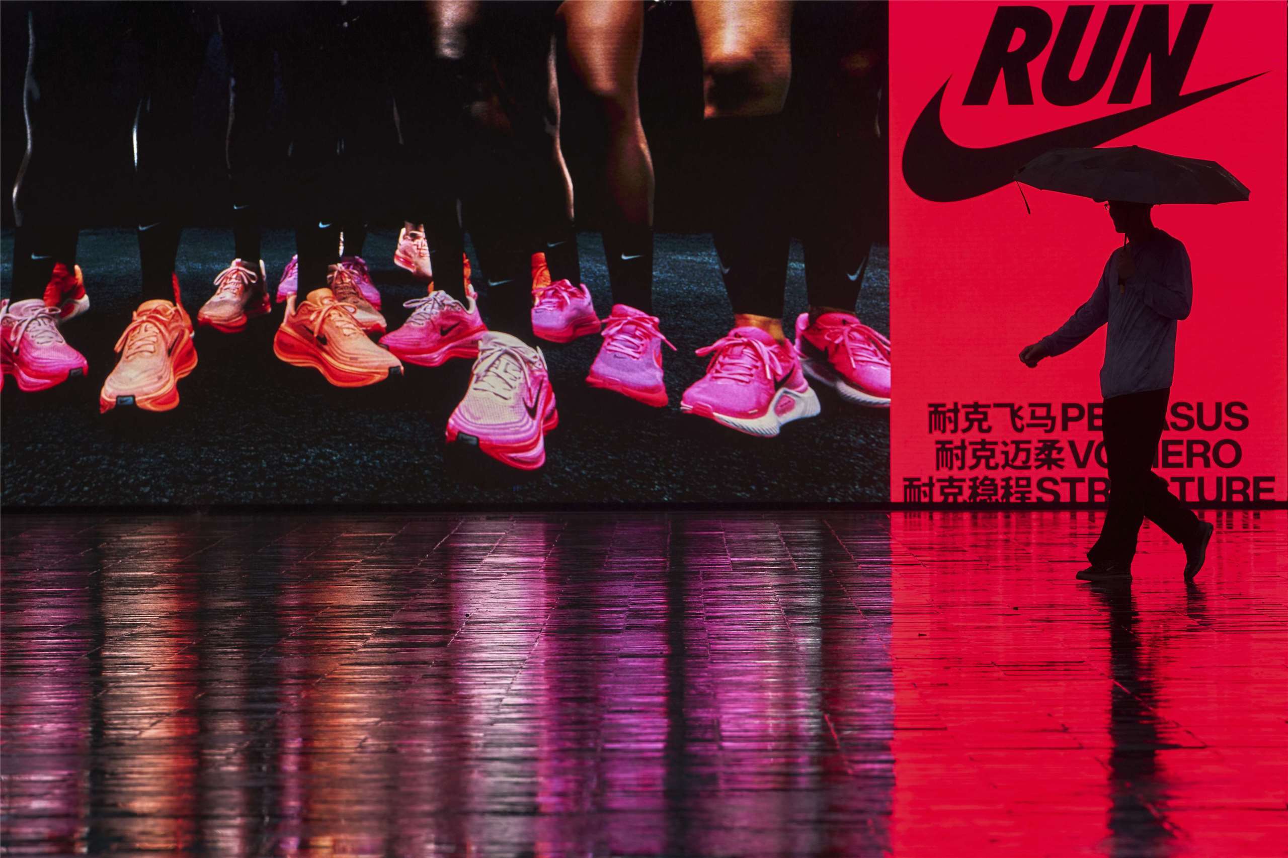 美國運動品牌Nike的中國市場曾經創下20季連續雙位數成長，如今在中國品牌安踏、李寧等快速崛起下，耐吉卻陷入單季雙位數衰退窘境。圖為一名中國男子撐傘走過北京一家耐吉商店前。(AFP)