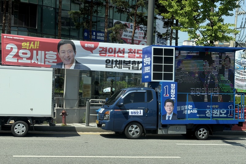 韓國地方選舉及國會議員補選將在6月3日登場。圖為首爾街頭造勢宣傳標語，左為國民力量候選人吳世勳的競選布條，右為共同民主黨候選人鄭愿伍的競選車。