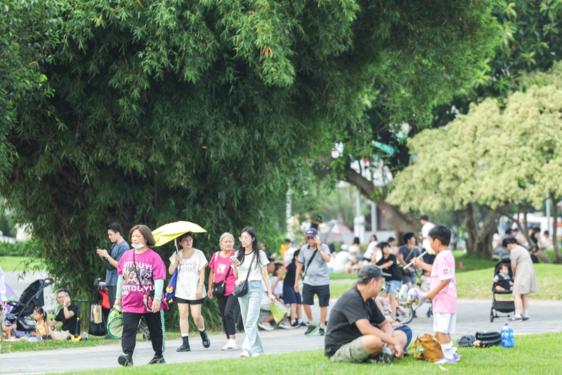 氣象署24日下午更新高溫資訊，其中雙北市為黃色燈號，需注意攝氏36度以上高溫。圖為台北花博公園午後人潮，有民眾待在樹蔭下休憩。
