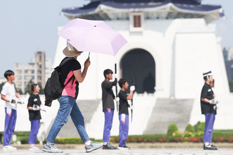 氣象署28日發布高溫資訊，其中新北、台南及花蓮留意可能連續出現攝氏38度極端高溫。圖為民眾撐著陽傘路過台北自由廣場。