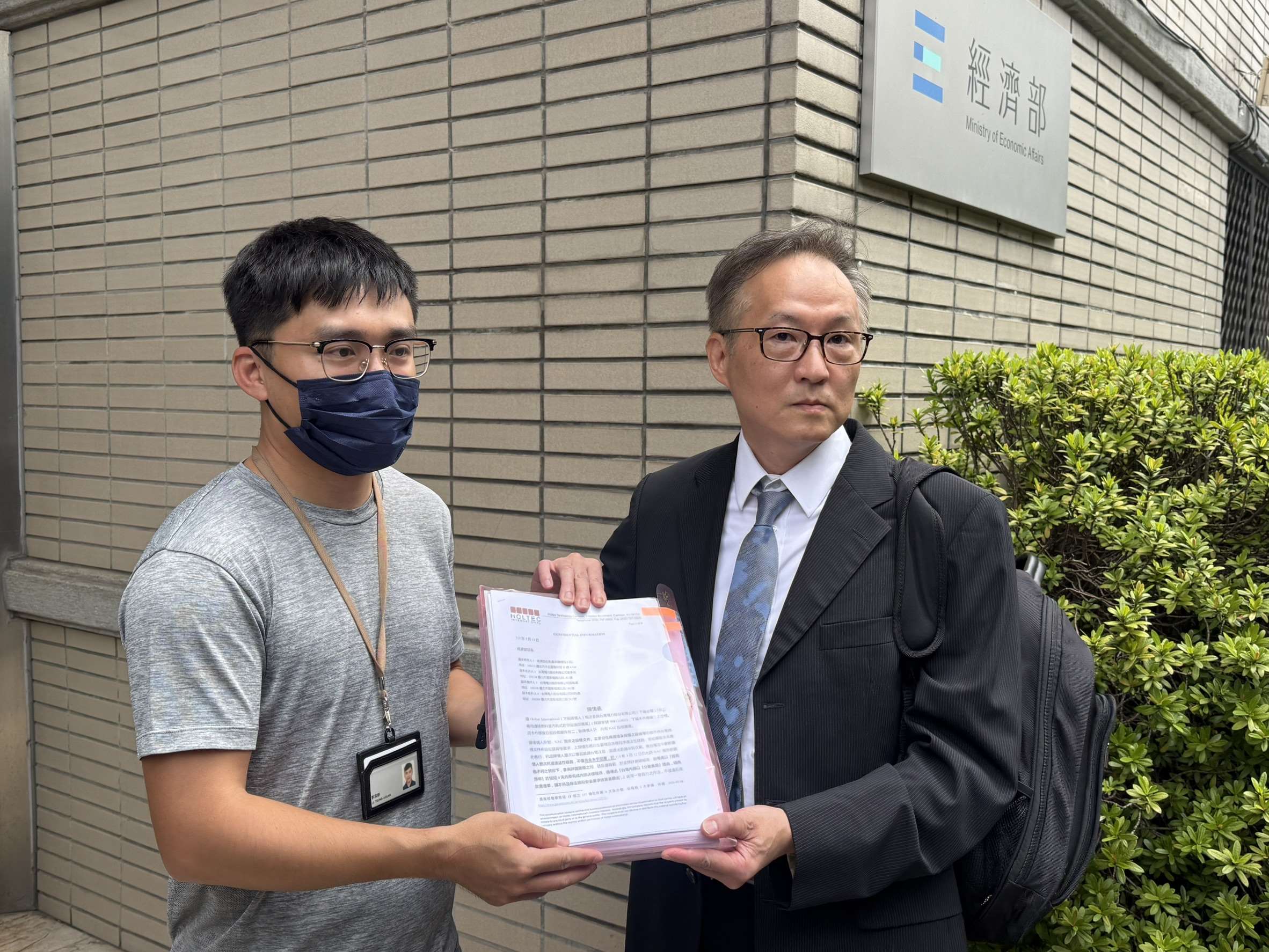 美商合泰公司委託律師郝燮戈(右)赴經濟部遞交陳情書，抗議台電核三乾貯設施採購黑箱，經濟部國營司承辦人李宗軒(左)出面收下陳情書。(謝佳興 攝)