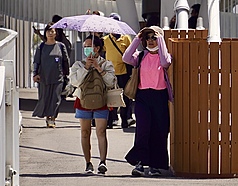 高雄天氣炎熱，駁二藝術特區周邊遊憩民眾戴起墨鏡防曬、撐傘遮陽。資料照片。
