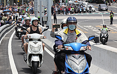 淡江大橋12日正式通車，卻有騎士在機車道停車後橫躺在路面量測車道寬度，公路局蒐集事證後已向警方舉發。圖為多名機車騎士在通車第一時刻上橋體驗。資料照。