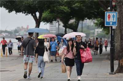 中央氣象署預報，梅雨季首波鋒面下週報到。圖為民眾在新北市淡水老街撐傘購物。(圖：中央社)