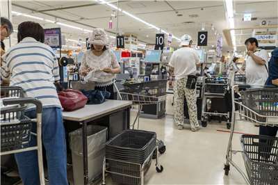 高市政府準備廢除食品消費稅實現競選承諾，卻因為日本商場超市收銀機設定打敗。圖為日本超市收銀台和顧客結帳後自助包裝區。(AFP)