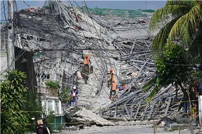 菲律賓馬尼拉附近一棟興建中的建築物25日發生倒塌，已知3人罹難、17人下落不明。圖為當地搜救人員進行搜救。(AFP)