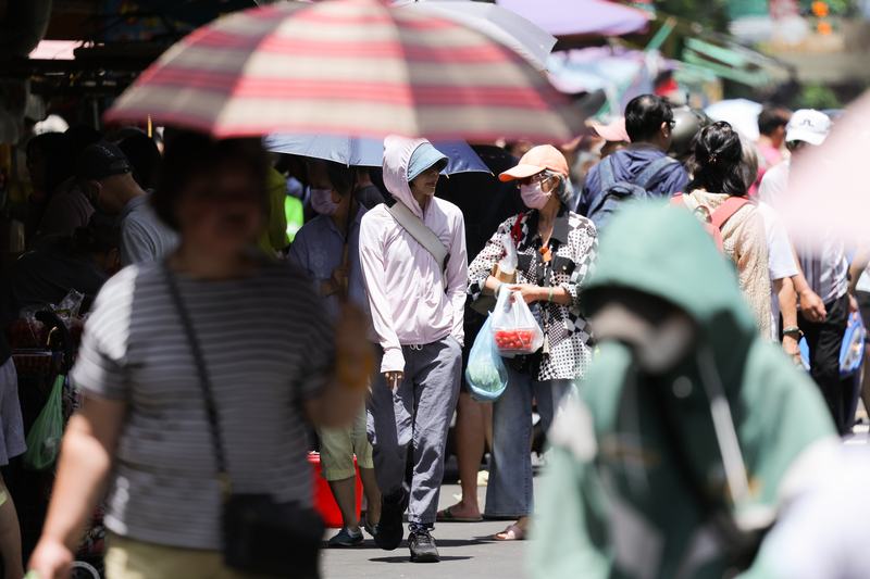 中央氣象署發布高溫資訊，各地天氣炎熱，21日白天新北市、彰化縣、南投縣、雲林縣、台南市、屏東縣、花蓮縣為橙色燈號，有機會連續出現36度高溫；台北市為黃色燈號，防36度以上高溫。圖為民眾穿著外套、撐傘、戴帽子遮陽。資料照。