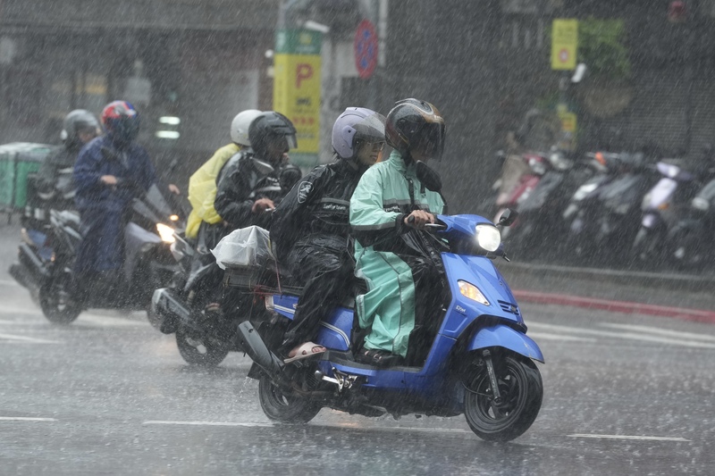受到鋒面接近和西南風增強影響，台北下大雨，松山區機車騎士在雨中前進。資料照片。