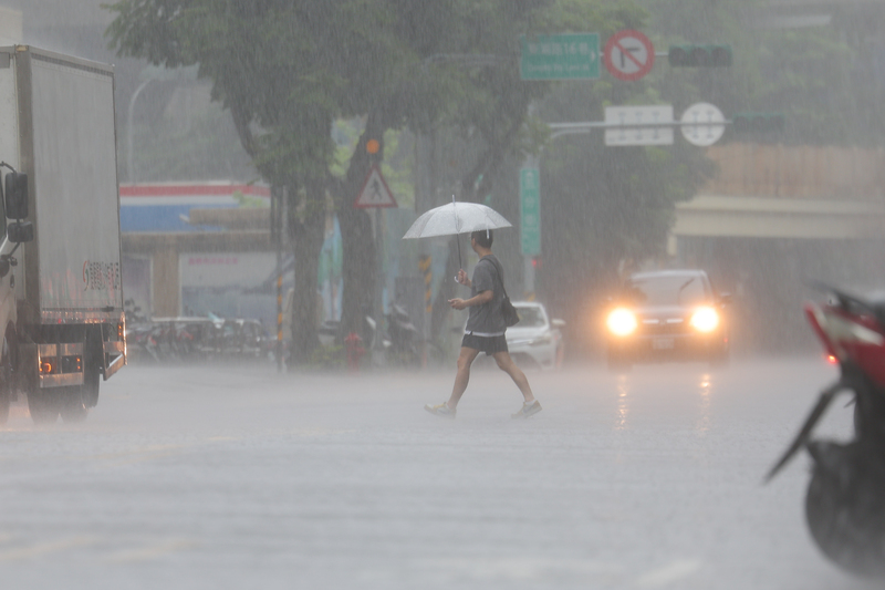 豪雨狂下，台北市內湖區民眾撐傘過馬路。資料照片。
