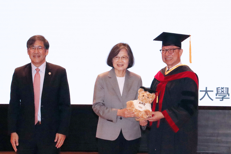 前總統蔡英文（中）13日出席高雄醫學大學畢業典禮，校長余明隆（右）致贈繡有「YBSG」的高醫大
畢業熊。