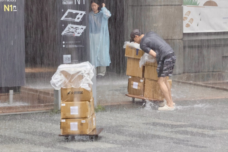 台北市今天(18日)午後降下豪雨，台北市政府統計，截至下午5時30分，接獲91件災情通報，其中75件為積淹水。圖為松山區一名快遞員在大雨中辛苦送貨。