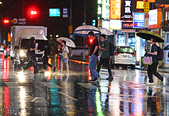 氣象署預測，梅雨鋒面預計從6月9日起影響到6月中旬之後，比較明顯的降雨是在9日、10日。圖為台北市區民眾晚間雨中撐傘過馬路。
