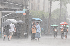 氣象署7日發布豪雨特報，對流雲系發展旺盛，易有短延時強降雨。圖為台北市中正區外出民眾在滂沱大雨中撐傘前行。