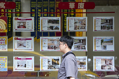 2025年建物買賣年減25.5%，9年新低。圖民眾經過台北市大安區一處房仲業櫥窗。