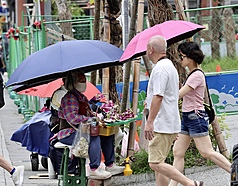 中央氣象署21日下午發布15縣市亮高溫燈號，其中雙北已出現逾38度高溫。圖為台北市萬華區民眾撐傘防曬。
