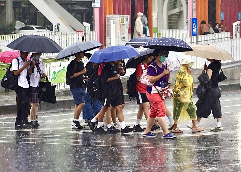 南部地區19、20日有不定時短暫陣雨或雷雨，且可能有局部大雨。圖為高雄市前鎮區午後陣
雨，行人撐傘過馬路。