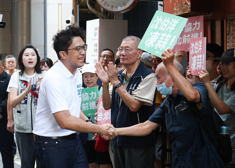 民進黨台北市長參選人沈伯洋（前左）18日上午前往直興市場拜票，獲得不少民眾歡迎，現場「凍蒜」聲不斷。