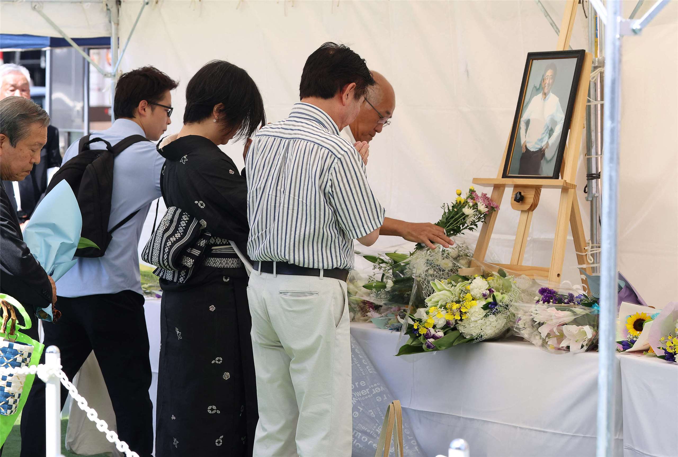 在安倍晉三於四年前遇刺的奈良縣奈良市槍擊案現場附近，今天(8日)仍有許多民眾紛紛前往獻花悼念。(AFP)