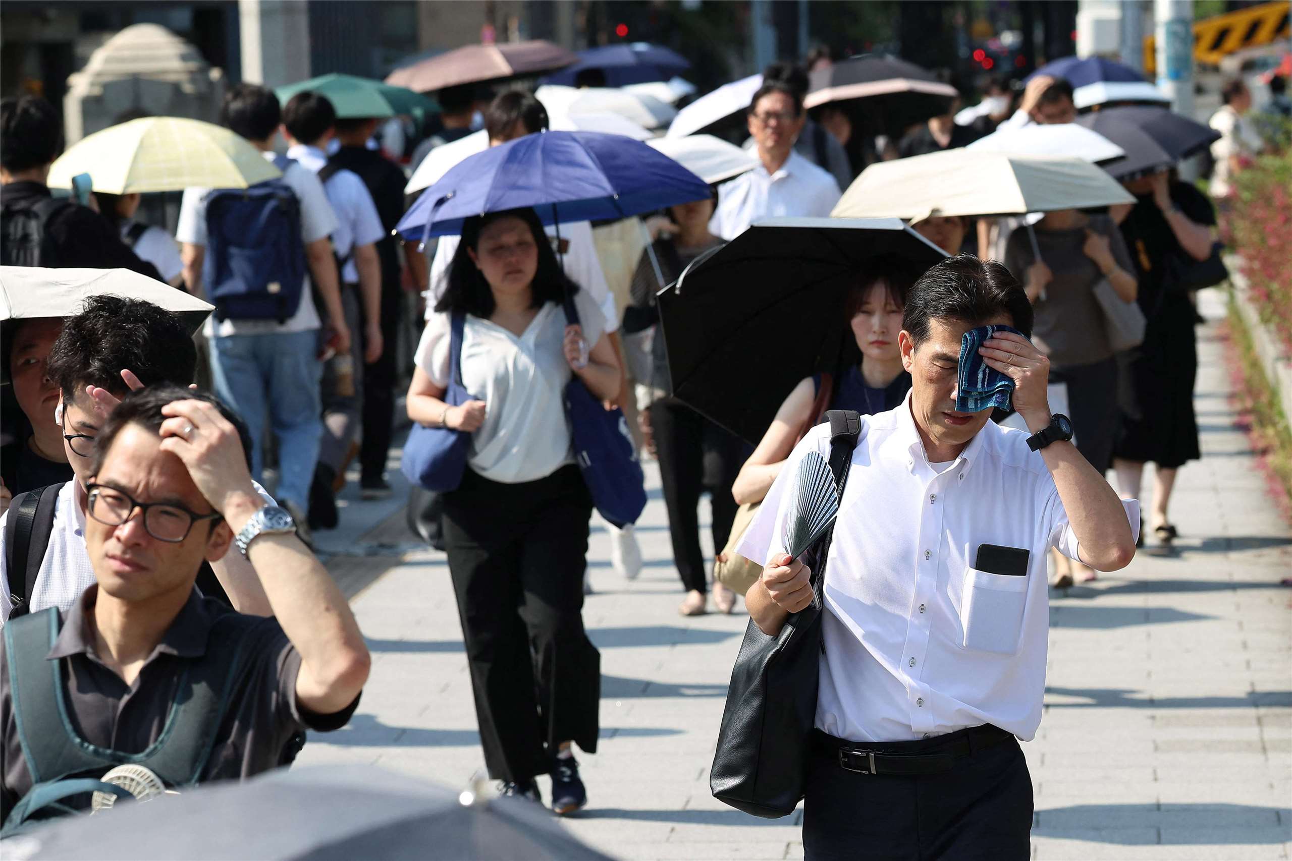 日本熱浪來襲，在大阪市區，有人揮汗如雨，有人忙著撑陽傘抵擋陽光照射。