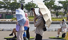 中央氣象署表示，西南風沉降影響，天氣高溫炎熱，台東縣已有焚風發生。圖為高雄駁二藝術特區周邊民眾撐傘遮陽。資料照。