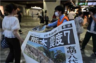 日本熊本縣28日下午4時27分左右發生規模7.1強震，熊本市內震感強烈。圖為《讀賣新聞》在人來人往的車站發送號外。(AFP)