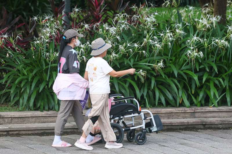 圖為外籍幫傭與雇主一同散步。資料照。
