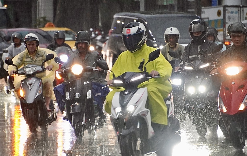 西南風偏強及低壓帶影響，南台灣連日豪大雨。圖為高雄市三民區機車騎士雨中騎行。