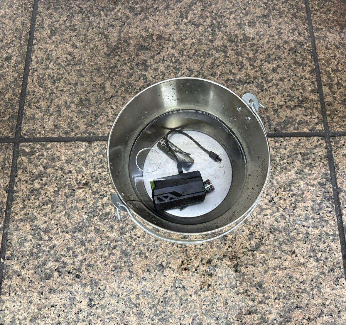 板南線台北車站旅客行動電源自燃， 經緊急處理後恢復正常。圖為行動電源浸泡冷水水桶。(台北捷運官網)