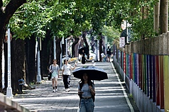 今天(1日)各地雲量偏多，各地高溫約攝氏32至35度。圖為民眾撐傘遮陽。資料照。