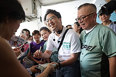 民進黨台北市長參選人沈伯洋（中）13日上午赴東門市場掃街，許多民眾在市場外等候，拿出物品請沈伯洋簽名留念。