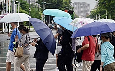 氣象署16日表示，未來一週台灣受大低壓帶影響，南部、東半部地區易有短暫陣雨。圖為高雄市民眾撐傘過馬路。資料照。