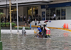 菲律賓正值雨季，大馬尼拉地區多處因豪雨而淹水，鉤端螺旋體病感染風險隨之升高。圖為在馬卡蒂市（Makati），有三輪車及民眾涉水而過。