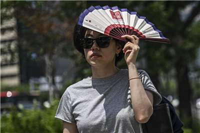 南韓於七月推出了新的高溫警報系統。圖為行人用扇子遮擋陽光。