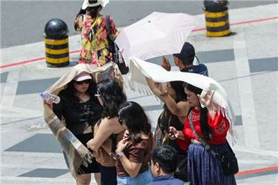 由於全球暖化、都市熱島效應，近年台灣夏季高溫屢創紀錄，熱傷害人數有逐年攀升趨勢。衛福部統計，7月熱傷害就診總計804人次。圖為觀光客中午在台北市信義區等待過馬路，拿圍巾遮陽防曬。