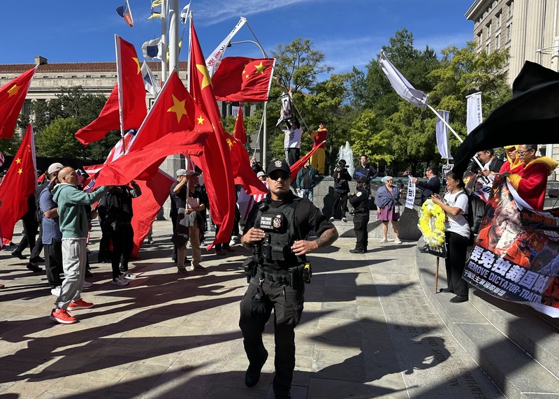 民主示威團體與中國僑團在美國國家檔案局前對峙揮舞旗幟，警方隔開雙方群眾。