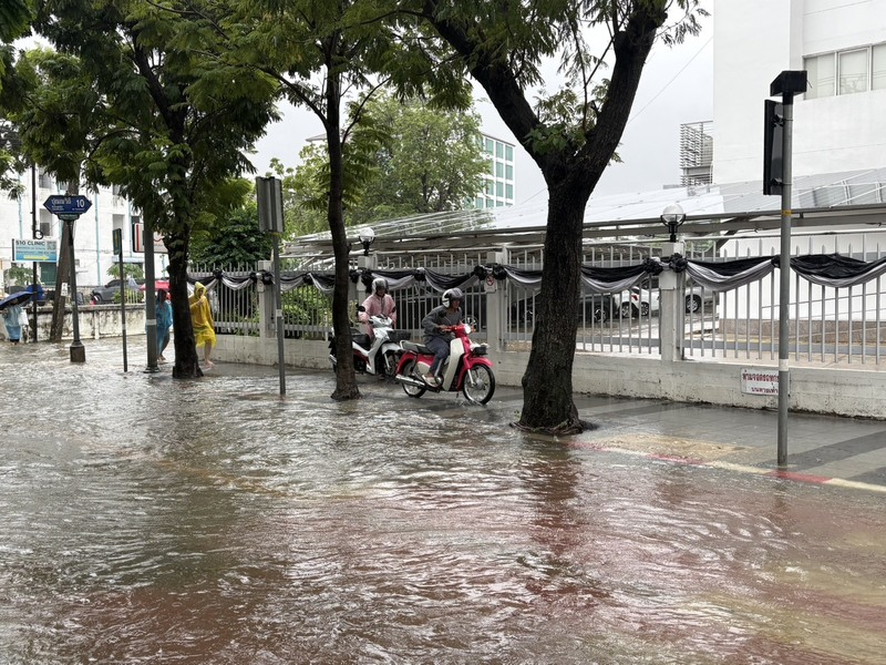 泰國曼谷26日持續降下大雨，多處道路出現淹水，民眾冒雨涉水通行，機車也受積水影響。（民眾提供）