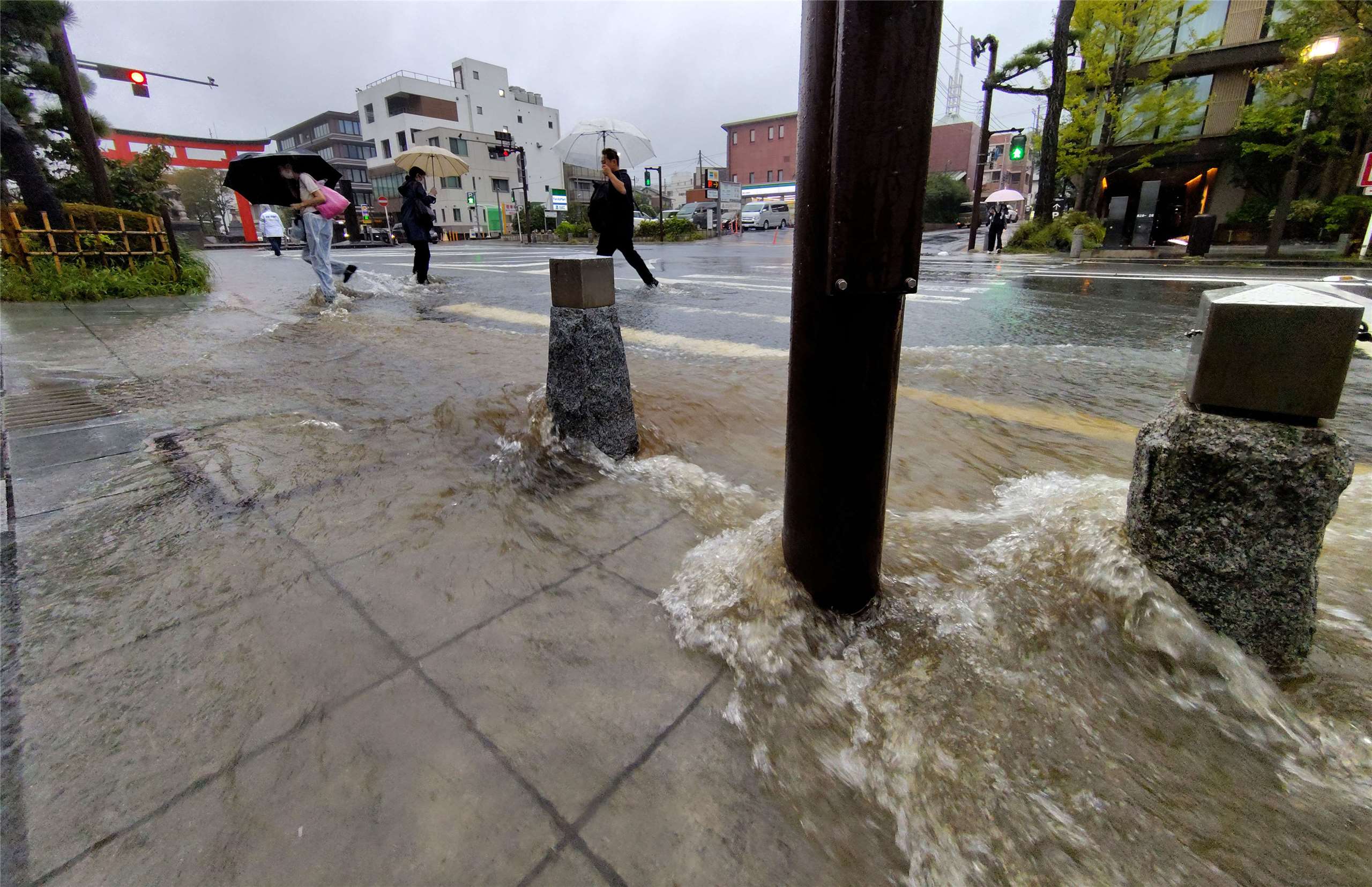 日本神奈川縣鎌倉市21日因颱風「杜鵑」帶來暴雨，街道積水湍急，民眾小心涉水通行。