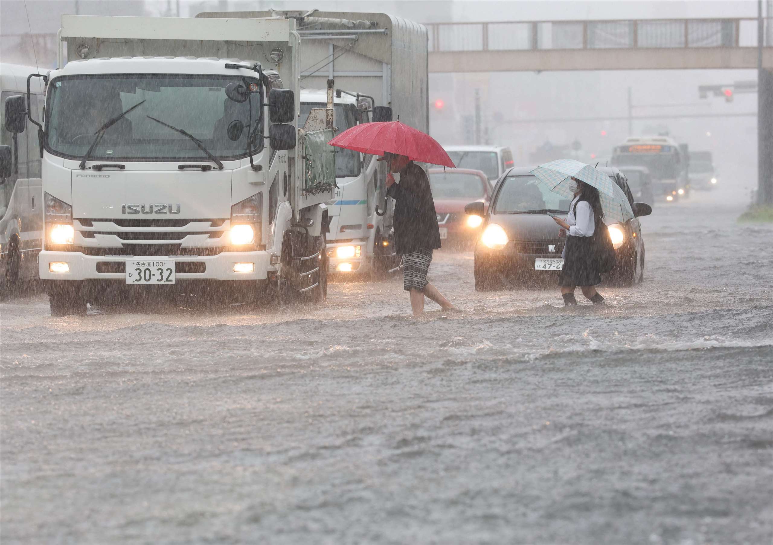 日本愛知縣名古屋市8日因暴雨導致道路淹水，民眾涉水前行。