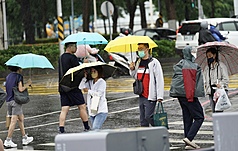 高雄天氣不穩定，民眾穿外套、撐傘過馬路。資料照片。