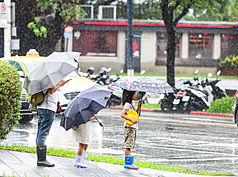 受到颱風外圍雲系影響，今天桃園以北降雨較為明顯，大台北地區及基隆北海岸並有大雨發生的機會，其他地區主要以午後降雨為主。圖為北市中正區街頭民眾撐傘準備過馬路。
