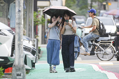氣象署表示，14日起東北季風增強，桃園以北、宜蘭與恆春半島要留意局部陣雨。圖為民眾一起撐一把傘走在台北街頭。