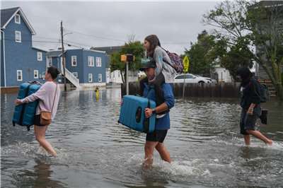美國國家氣象局指出，強烈東北風暴(Nor'easter)將持續為中大西洋(Mid-Atlantic)及新英格蘭(New England)地區帶來沿海淹水、強勁離岸流、強陣風及豪雨，惡劣天候預計將一路持續至28日。圖為一家人帶著物品涉水穿過被淹沒的道路。