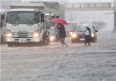 日本愛知縣名古屋市8日因暴雨導致道路淹水，民眾涉水前行。