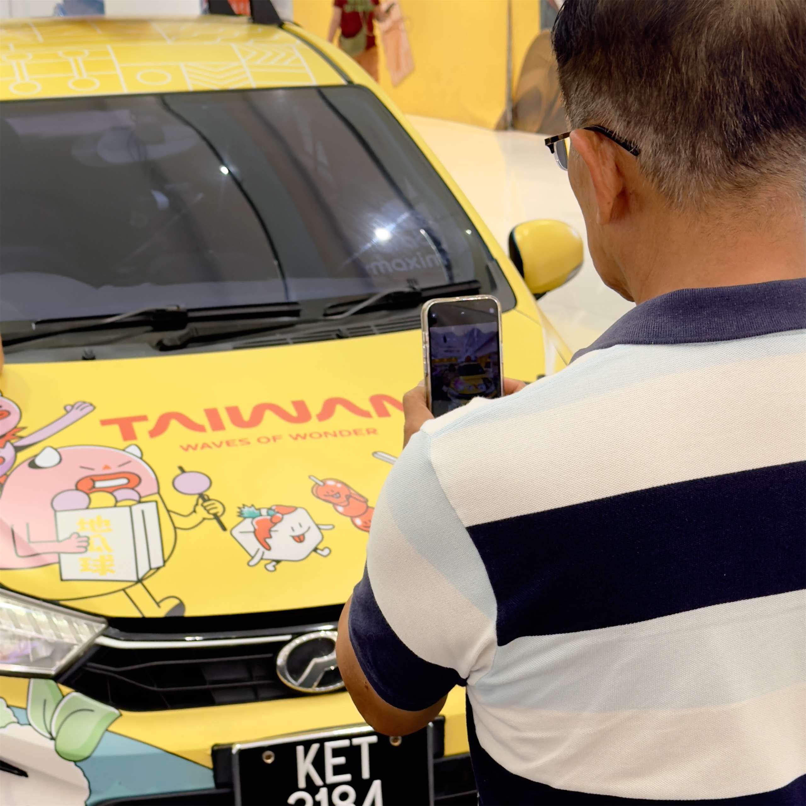民眾拿起手機捕捉主題車的亮眼外型,把這份「大馬遇見台灣」的瞬間記錄下來。(張欣薇攝影)