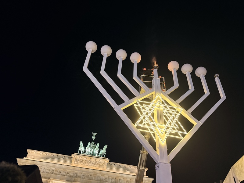 柏林猶太社群14日晚間在布蘭登堡門前舉行光明節點燈儀式，雲梯車升至高空，由猶太拉比點燃高約10公尺的光明節燭台第一道燭光。