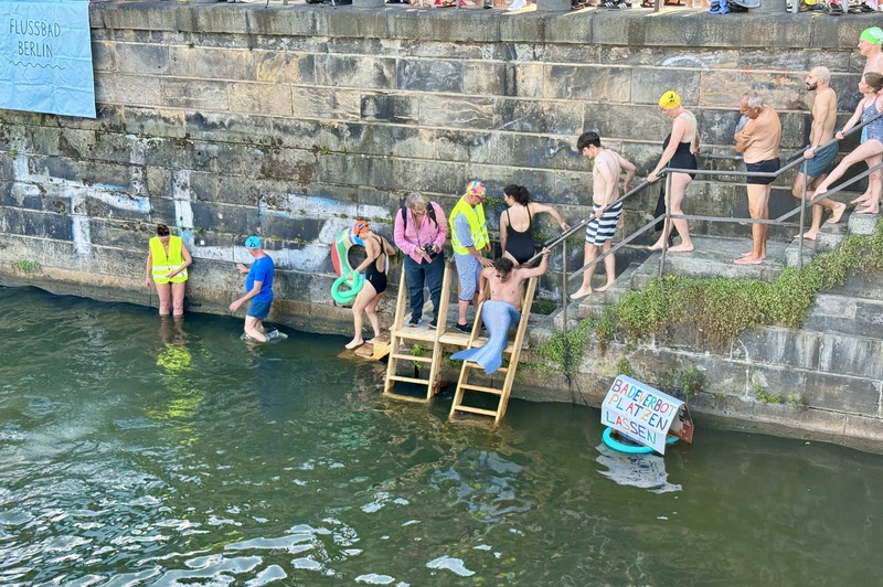 柏林市中心史普里河舉行游泳抗議活動，河上漂浮「打破游泳禁令」標語，有抗爭者穿人魚裝入水，表達想自由在城市河水中游泳的渴望。
