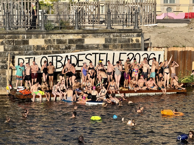 柏林市中心史普里河舉行游泳抗議活動，抗爭者聚集在臨時搭建的親水平台上，身後懸掛「2026年試辦河泳區！」布條，呼籲市府解除市中心百年禁泳令。