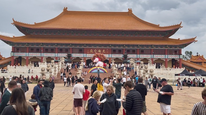 南非南華寺新春活動吸引大批僑胞與當地民眾湧入大雄寶殿前廣場，參與祈福與蔬食品嘗會，現場人潮絡繹不絕。